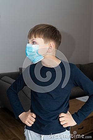 Child boy in blue medical mask in coronavirus quarantine at home. Epidemic control of COVID19 and proper prevention of Stock Photo