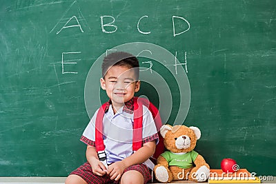 Child boy kindergarten preschool in student uniform with school bag, book sit with teddy bear Stock Photo