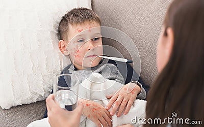 Child Boy With Measles Measuring Temperature, Lying on Sofa Stock Photo