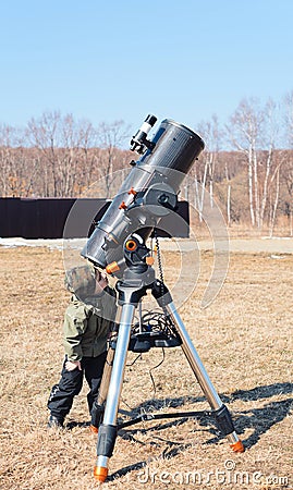 Child boy near big black telescope on a tripod at the observatory for observation of stars and planets. Science Stock Photo