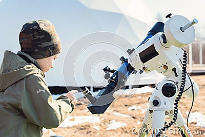 Child boy near the telescope on a tripod at the observatory for observation of stars and planets. Science, astronomy Stock Photo