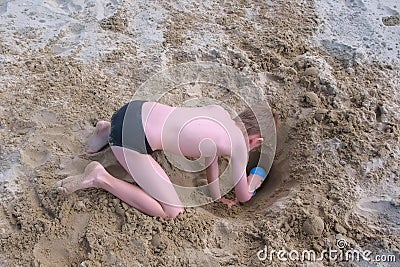 Child boy playing on sand beach digging shovel deep hole on summer vacation. Stock Photo