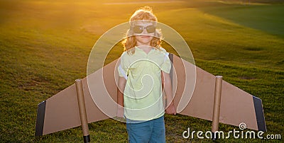 Child boy playing with toy airplane wings at sunset. Dream of becoming a pilot. Superhero flying. Stock Photo