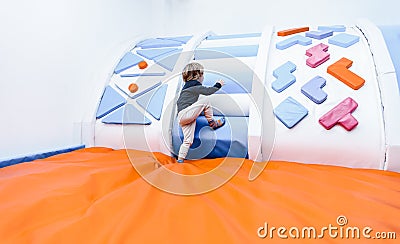 Child boy son plays in the children`s room with inflatable trampolines, climbs the slide active game indoor Stock Photo