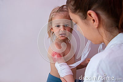 Pediatrician is dressing wound on toddler arm with a sterile non-adhesive bandage Stock Photo