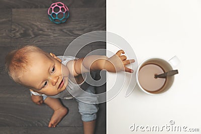 Child burn and scald injury concept - little boy reaching for hot drink mug on the table Stock Photo