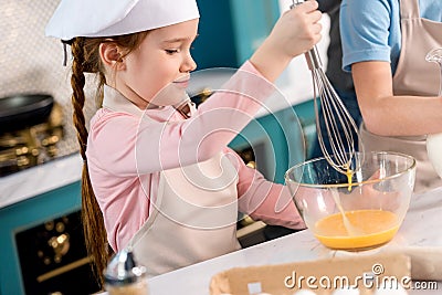 child in chef hat and apron whisking eggs Stock Photo