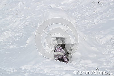 The child climbs out of the snow cave - dwelling Inuit, Igloo Stock Photo