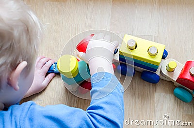 The child collects a toy wooden train. Stock Photo