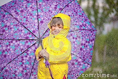 Rainy day. Happy toddler girl wearing waterproof coat with umbrella. Stock Photo