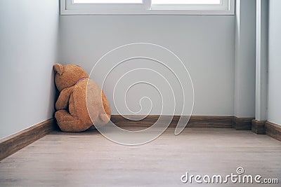 Child concept of sorrow. Teddy bear sitting leaning against the wall of the house alone, look sad and disappointed Stock Photo
