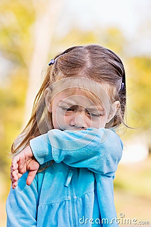 Child coughing or sneezing into arm Stock Photo