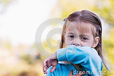 Child coughing or sneezing into arm Stock Photo