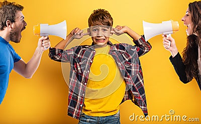 Child covers his ears because he does not want to hear the cries and reproaches of his parents. Yellow background Stock Photo