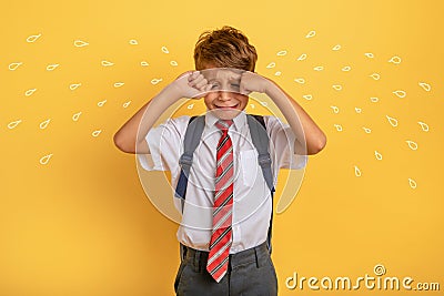 Child cries because does not want to go to school. Yellow background Stock Photo