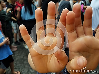 Child in crowd with hands in front of face Stock Photo