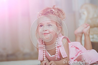 Child with cute smile in pink dress lie on carpet Stock Photo