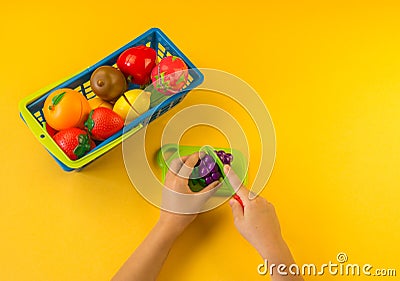 A child cuts a plastic fruit on a board Stock Photo