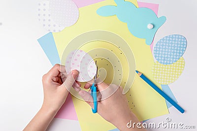 Child cutting out easter egg with scissors. Stock Photo