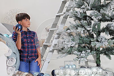 Child decorate the christmas tree with balls and ladder at home Stock Photo