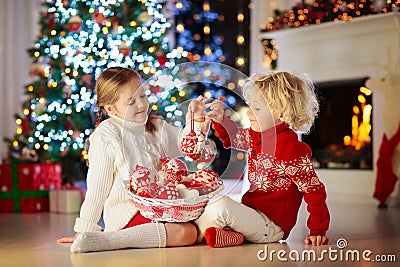 Child decorating Christmas tree at home. Little boy and girl in knitted sweater with handmade Xmas ornament. Family celebrating Stock Photo