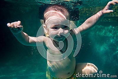 The child dives under the water in the pool accompanied by a coach Stock Photo