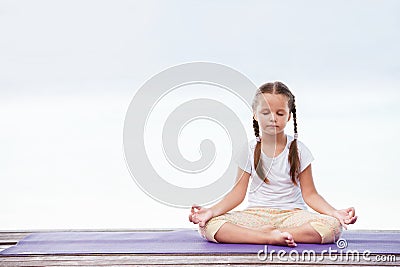 Child doing exercise on platform outdoors. Healthy lifestyle. Yoga girl Stock Photo