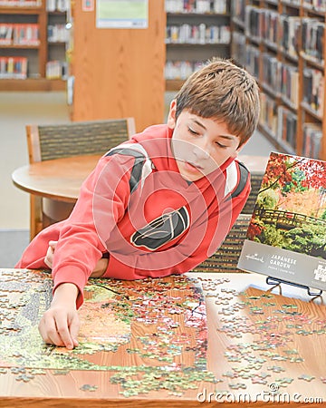 Child Doing A Jigsaw Puzzle at Library Editorial Stock Photo
