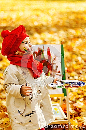 Child drawing on easel in Autumn Park. Creative kids development Stock Photo