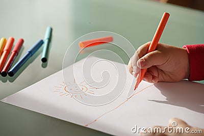 Child drawing a sun with colorful markers Stock Photo