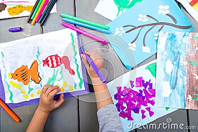 Child drawing. Top view of child hands with pencil painting picture on paper. Kid drawings. Stock Photo