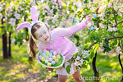 Child with bunny ears on garden Easter egg hunt Stock Photo