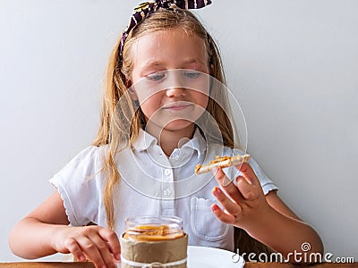 Child eating crispbread peanut butter sitting at table in kitchen at home. Nutritious superfood vegan healthy lifestyle Stock Photo