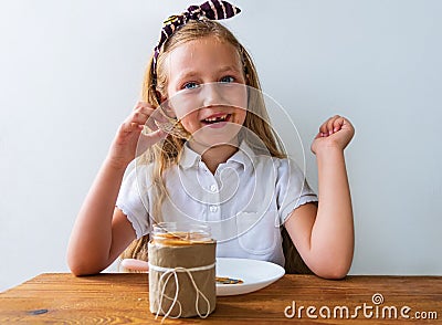 Child eating crispbread peanut butter sitting at table in kitchen at home. Nutritious superfood vegan healthy lifestyle Stock Photo