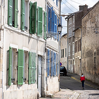 child on electric scooter passes green and blue shutters in small french burgundy town Editorial Stock Photo