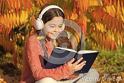 Child enjoy reading. Studying twice faster using visual and audio information. Girl read book on autumn day. Little Stock Photo