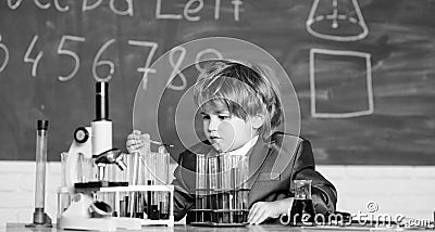 Child enjoy studying. Knowledge concept. Boy near microscope and test tubes in school classroom. Kid study biology Stock Photo