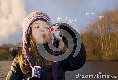 Child enjoys playing with soap bubbles at sunset Stock Photo