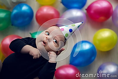 Child in a festive cap in polka-dot lies on his hands against Stock Photo