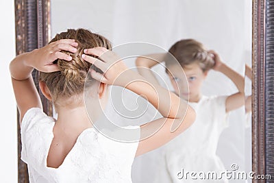 Child fixing her hair while looking in the mirror. Stock Photo