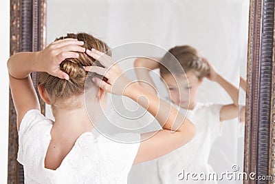 Child fixing her hair while looking in the mirror. Stock Photo