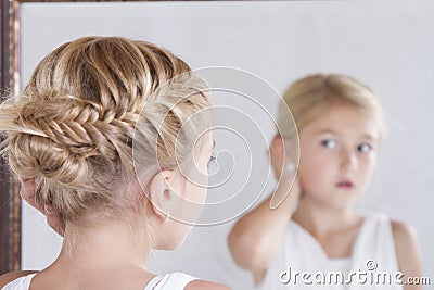 Child fixing her hair while looking in the mirror. Stock Photo