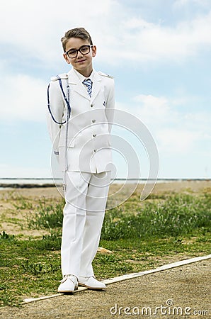 Child with formal pose, with arms on his back dressed in the communion sailor suit on the beach Stock Photo