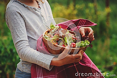 Child with fresh farm organic salad in wooden plate in summer garden Stock Photo