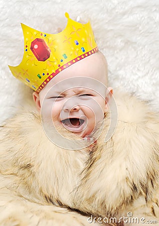 Child in a fur cape and crown on a white background. baby crying Stock Photo