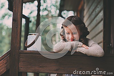 Child girl with candle holder relaxing in evening at cozy country house. Stock Photo