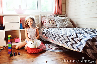 Child girl cleaning her room and organize wooden toys into knitted storage bag Stock Photo