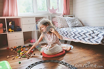 Child girl cleaning her room and organize wooden toys into knitted storage bag Stock Photo