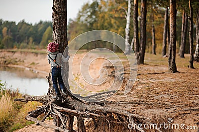 Child girl climbing old pine tree on the walk on river side Stock Photo