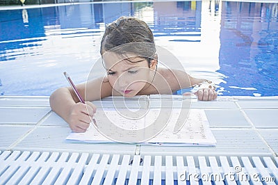 Child girl doing holidays homework over swimming poolside Stock Photo